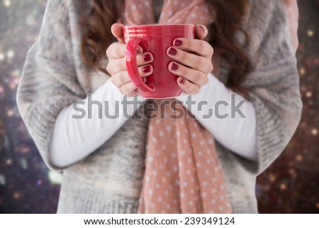 Woman in winter clothes holding a hot drink against blurred lights