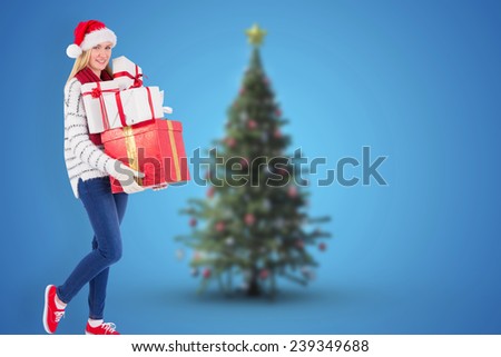 Festive blonde holding pile of gifts against blurry christmas tree