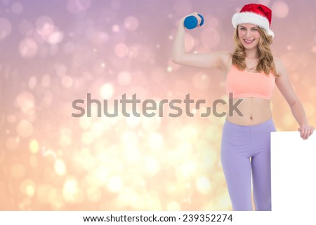 Festive fit blonde smiling at camera holding poster against pink abstract light spot design