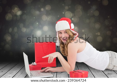 Happy woman laying on the floor while using her laptop against shimmering light design over boards