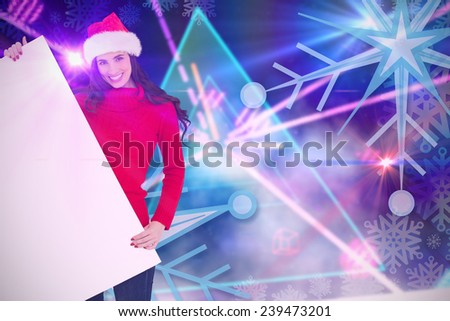 Smiling brunette in santa hat showing white poster against digitally generated laser lights background