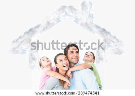 Happy young family looking up together against house outline in clouds