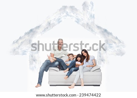 Family sitting on sofa smiling at camera against house outline in clouds