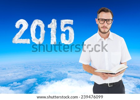 Geeky young man reading from black book against blue sky over white clouds