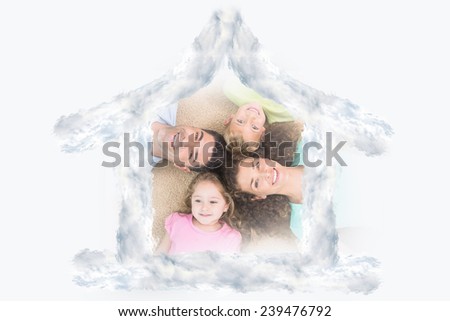 Happy family lying on the rug in a circle against house outline in clouds
