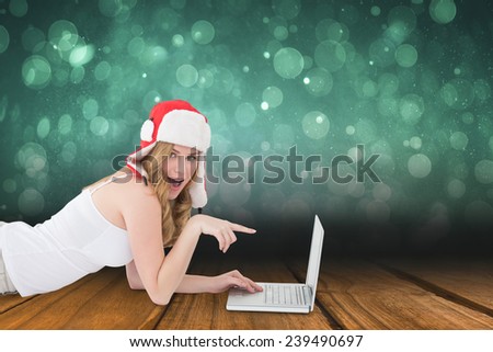 Woman lying on the floor while pointing to laptop against shimmering light design over boards