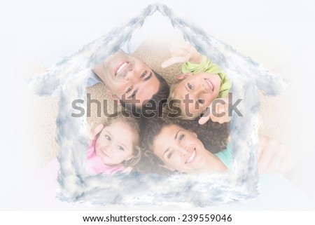 Smiling family lying on the rug in a circle showing thumbs up against house outline in clouds