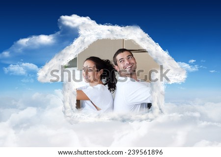 Radiant couple with unpacking boxes moving to a new house against bright blue sky with clouds
