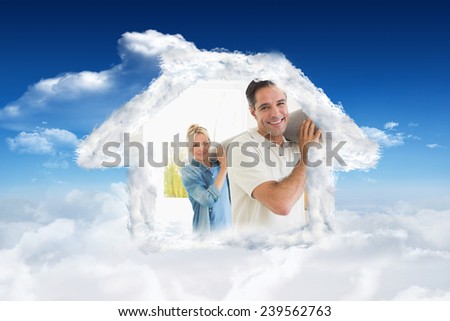 Couple carrying rolled rug after moving in a house against bright blue sky with clouds