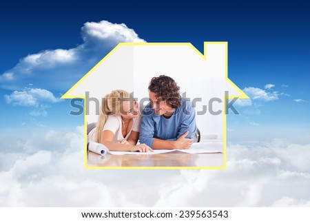 Smiling couple moving in a new house against bright blue sky with clouds
