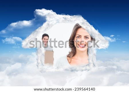 Pretty woman holding boxes in her new house against bright blue sky with clouds