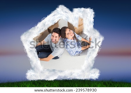 Overview of a couple sitting back-to-back against green grass under blue and purple sky