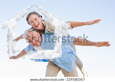 Happy casual couple having fun against house outline in clouds