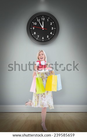 Elegant blonde with shopping bags and gifts against room with wooden floor