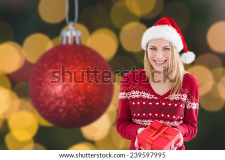 Woman smiling with present in hands against red christmas ball decoration hanging