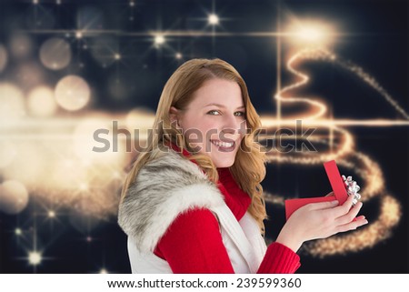 Surprised woman opening gift while looking at camera against christmas light design