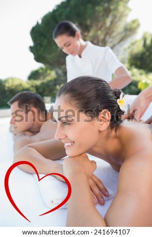 Attractive couple enjoying couples massage poolside against heart
