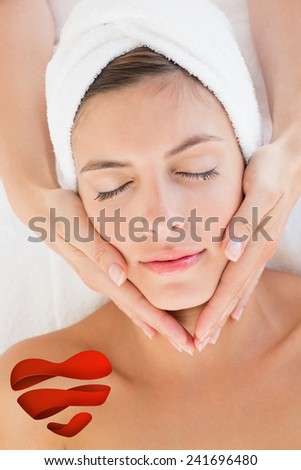 Attractive woman receiving facial massage at spa center against heart
