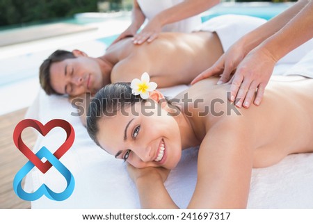Attractive couple enjoying couples massage poolside against linking hearts