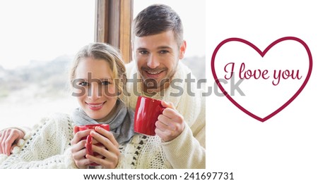 Loving couple in winter clothing with coffee cups against window against valentines love hearts
