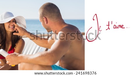Handsome man applying sun cream on his girlfriends nose against valentines love hearts