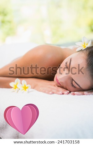 Beautiful woman lying on massage table at spa center against heart