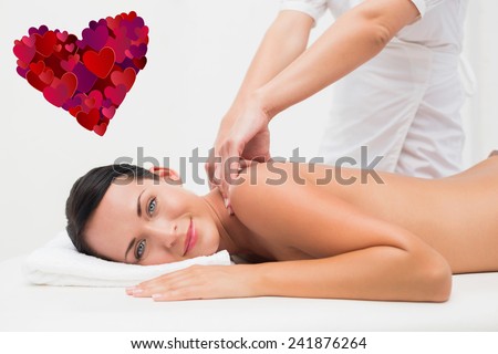 Beautiful brunette enjoying a back massage smiling at camera against heart