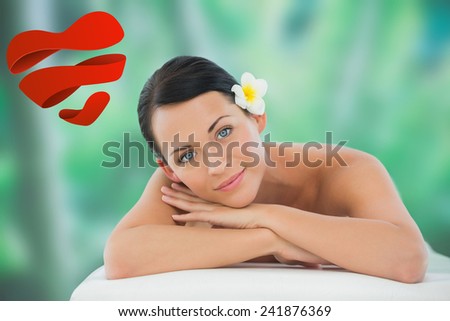Beautiful brunette relaxing on massage table smiling at camera against heart