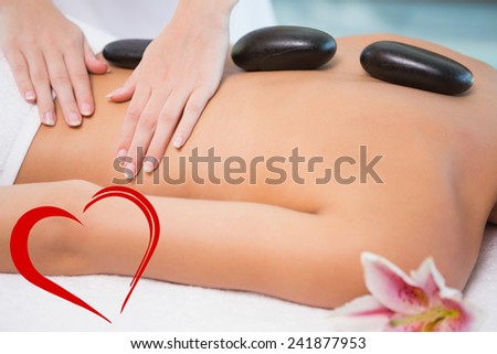 Beautiful woman receiving stone massage at health farm against heart