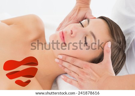 Attractive young woman receiving facial massage at spa center against heart