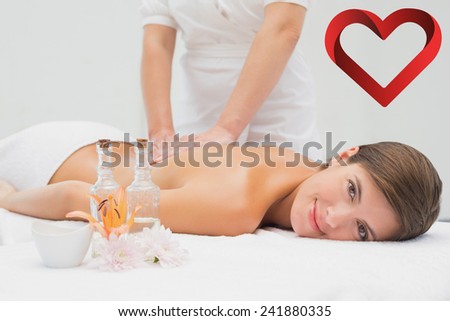 Attractive young woman receiving back massage at spa center against heart