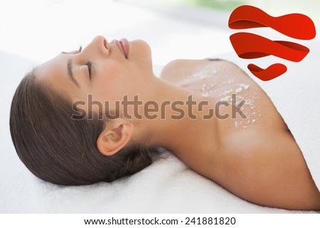 Beautiful brunette lying on massage table with salt scrub on chest against heart
