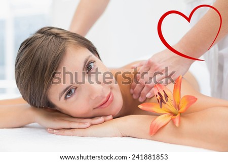 Attractive woman receiving shoulder massage at spa center against heart
