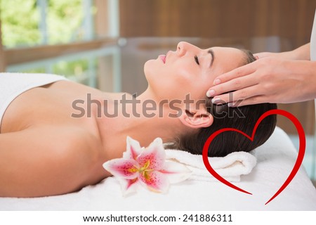 Attractive woman receiving head massage at spa center against heart
