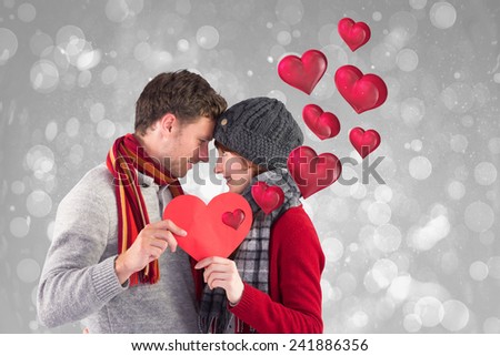 Couple holding a red heart against grey abstract light spot design