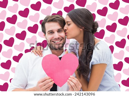 Pretty brunette giving boyfriend a kiss and her heart against valentines day pattern