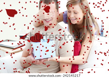 Smiling woman giving a present to her boyfriend against love heart pattern