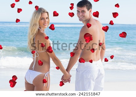 Rear view of couple holding hands looking against valentines heart design