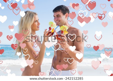Happy young couple holding cocktails against valentines heart design