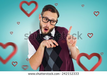 Geeky hipster in sweater vest pointing against blue vignette background