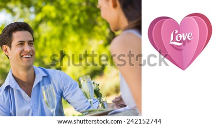 Couple with champagne flutes sitting at an outdoor cafÃ?Â© against love heart