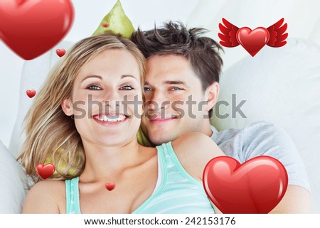Portrait of an attractive couple hugging and relaxing on the sofa against hearts