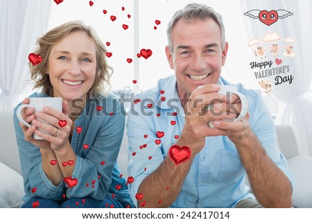 Smiling middle aged couple sitting on the couch having coffee against cute valentines message