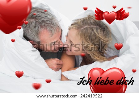 Loving middle aged couple under the duvet against ich liebe dich
