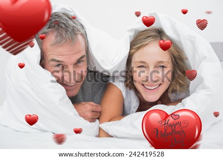 Happy middle aged couple under the duvet against happy valentines day