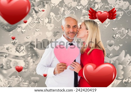 Handsome man holding paper heart getting a kiss from wife against grey valentines heart pattern