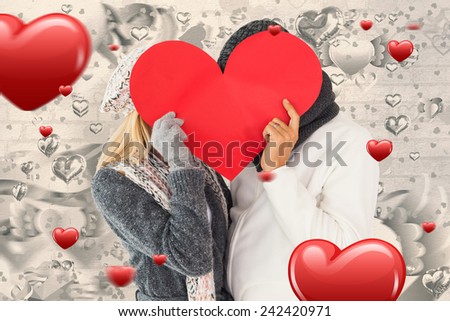 Couple in winter fashion posing with heart shape against grey valentines heart pattern