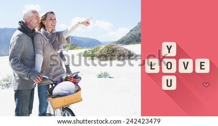 Carefree couple going on a bike ride and picnic on the beach against love you tiles