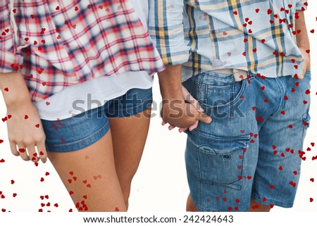 Couple in check shirts and denim holding hands against red love hearts