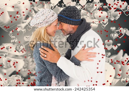 Happy couple in winter fashion embracing against grey valentines heart pattern
